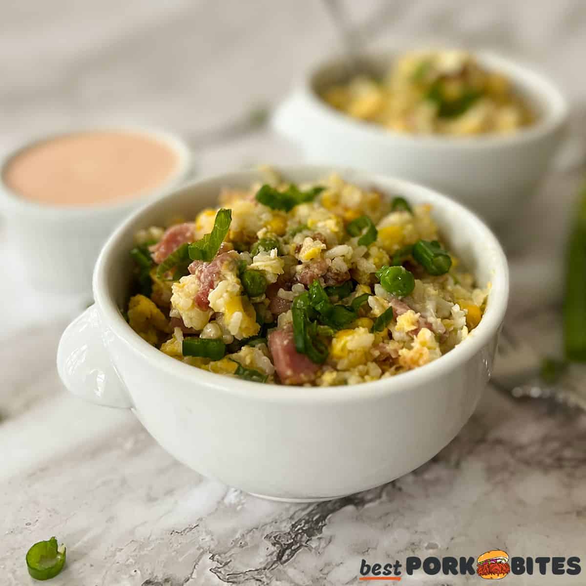 ham fried rice in white bowl with yum yum sauce in the background