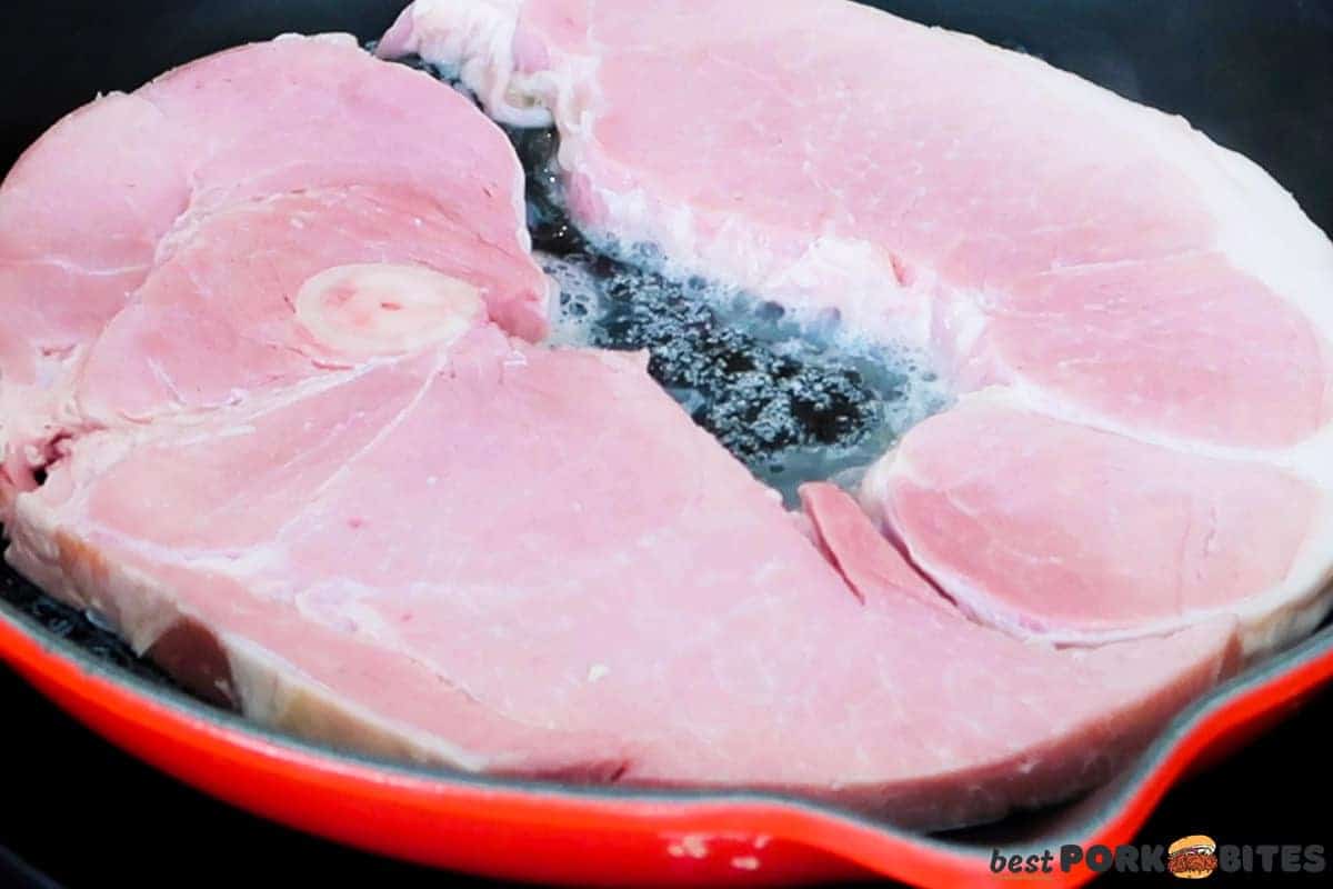 two ham steaks in a skillet with melted butter