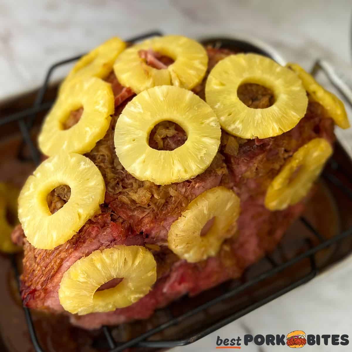 a baked ham with pineapple rings on a baking rack