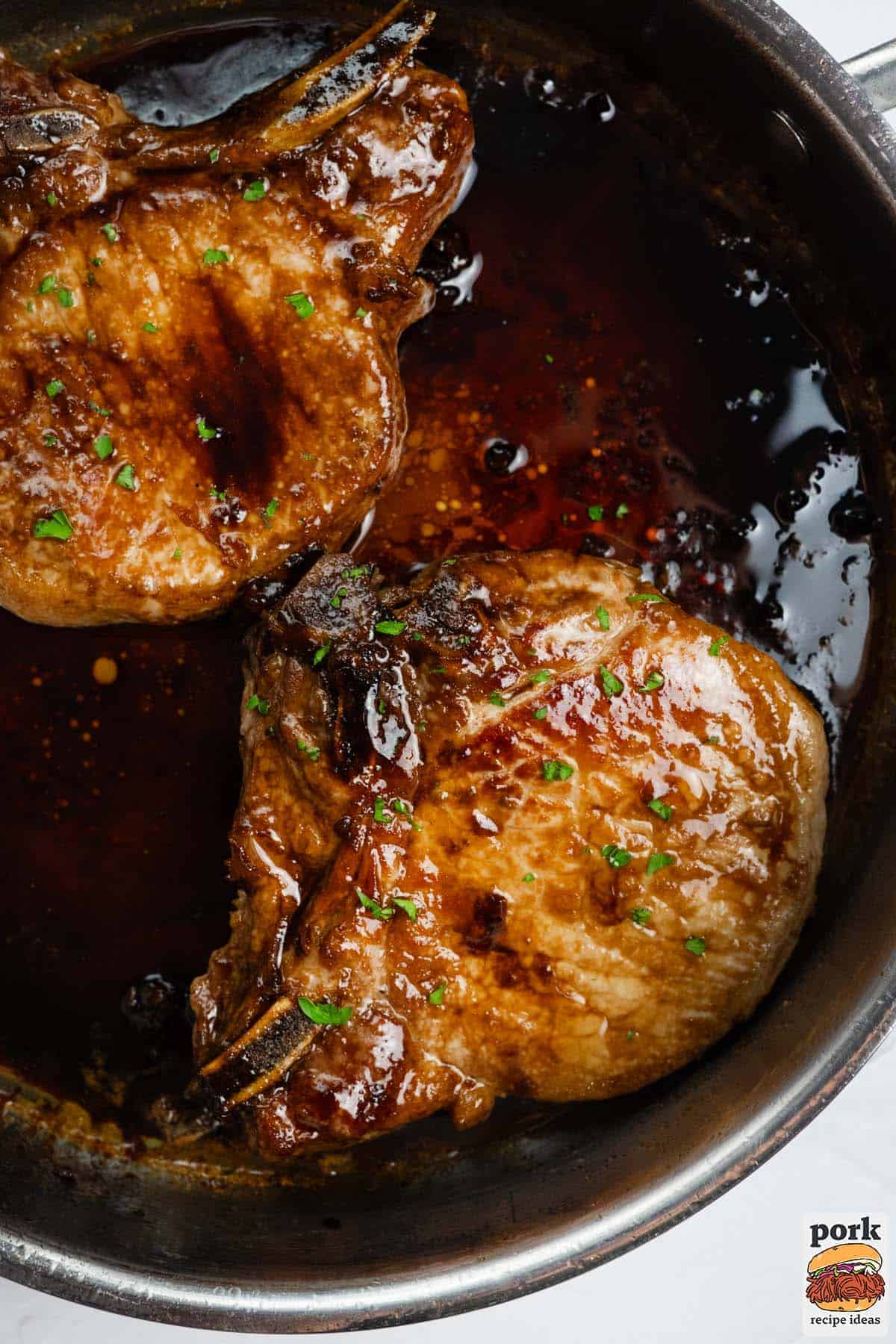 pork chops in a pan filled with glaze