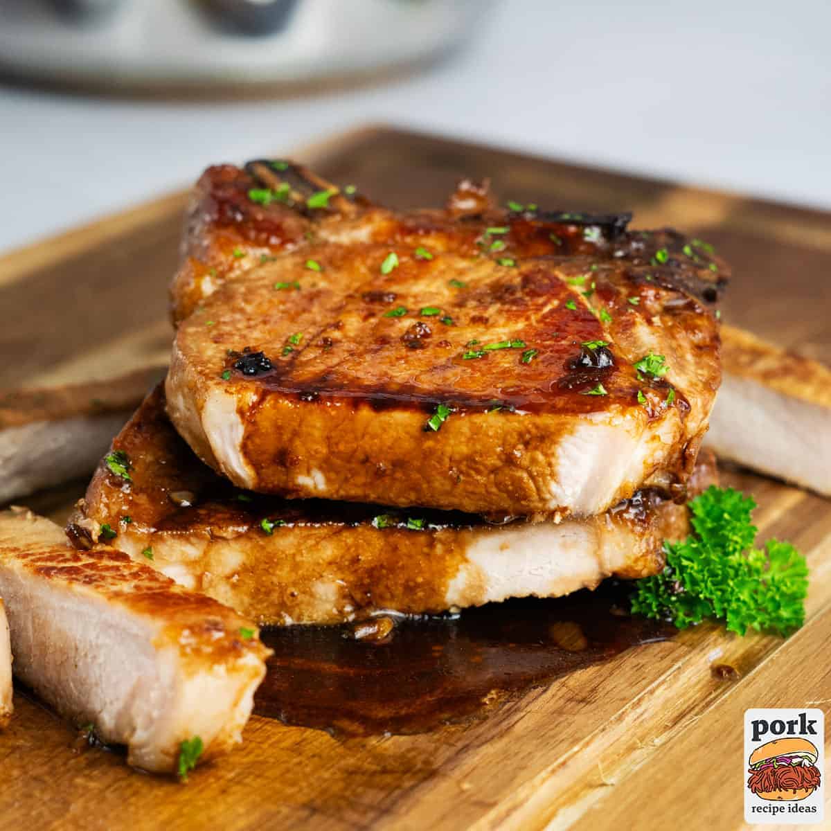 pork chops stacked on a cutting board with glaze