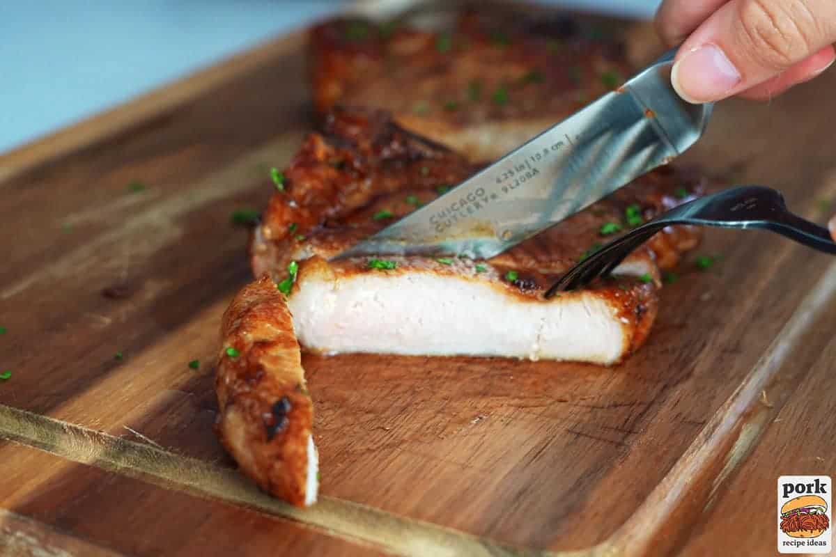 slicing a pork chop on a cutting board