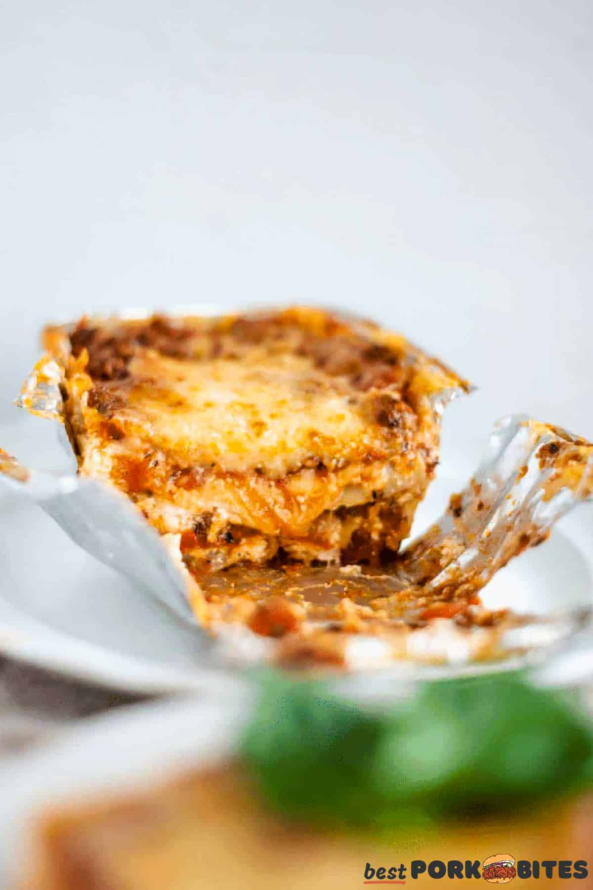 an aluminum baking tin with half a lasagna on a white plate
