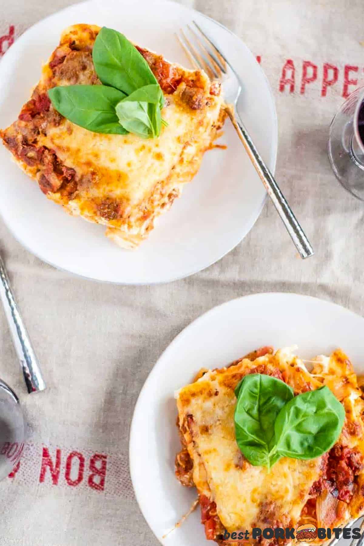 two plates of italian sausage lasagna with forks