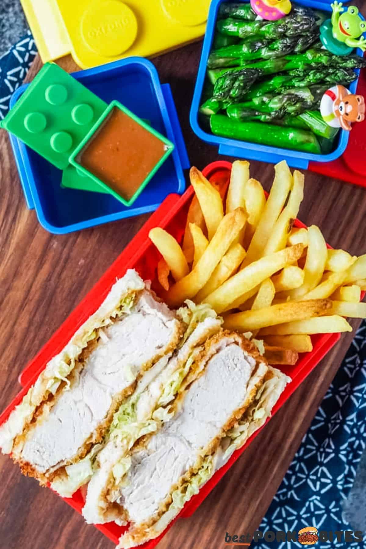 katsu sando, fries, asparagus and katsu sauce in separate colorful containers