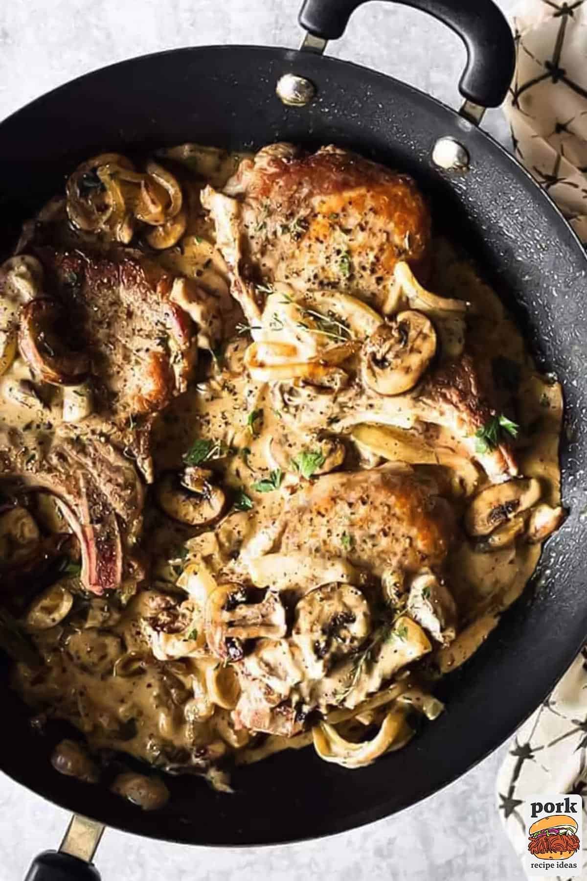 a pan filled with pan fried pork chops and mushroom gravy