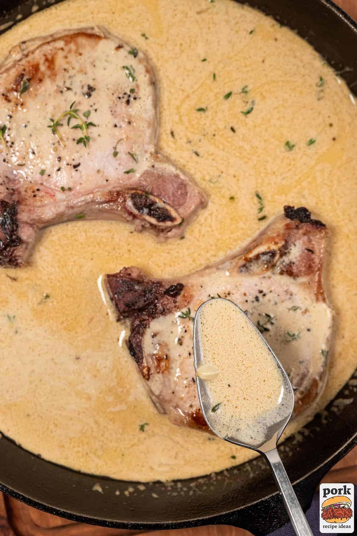 a spoon pouring mustard sauce on to pork chops in a pan