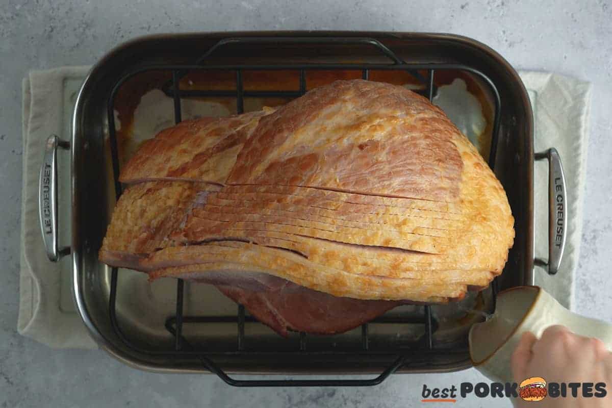 adding stock to baking dish for oven baked ham
