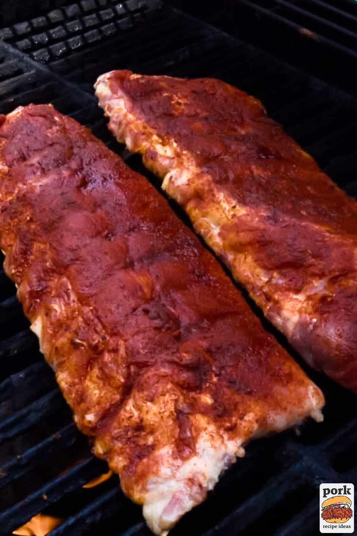 two seasoned pork rib racks on a grill