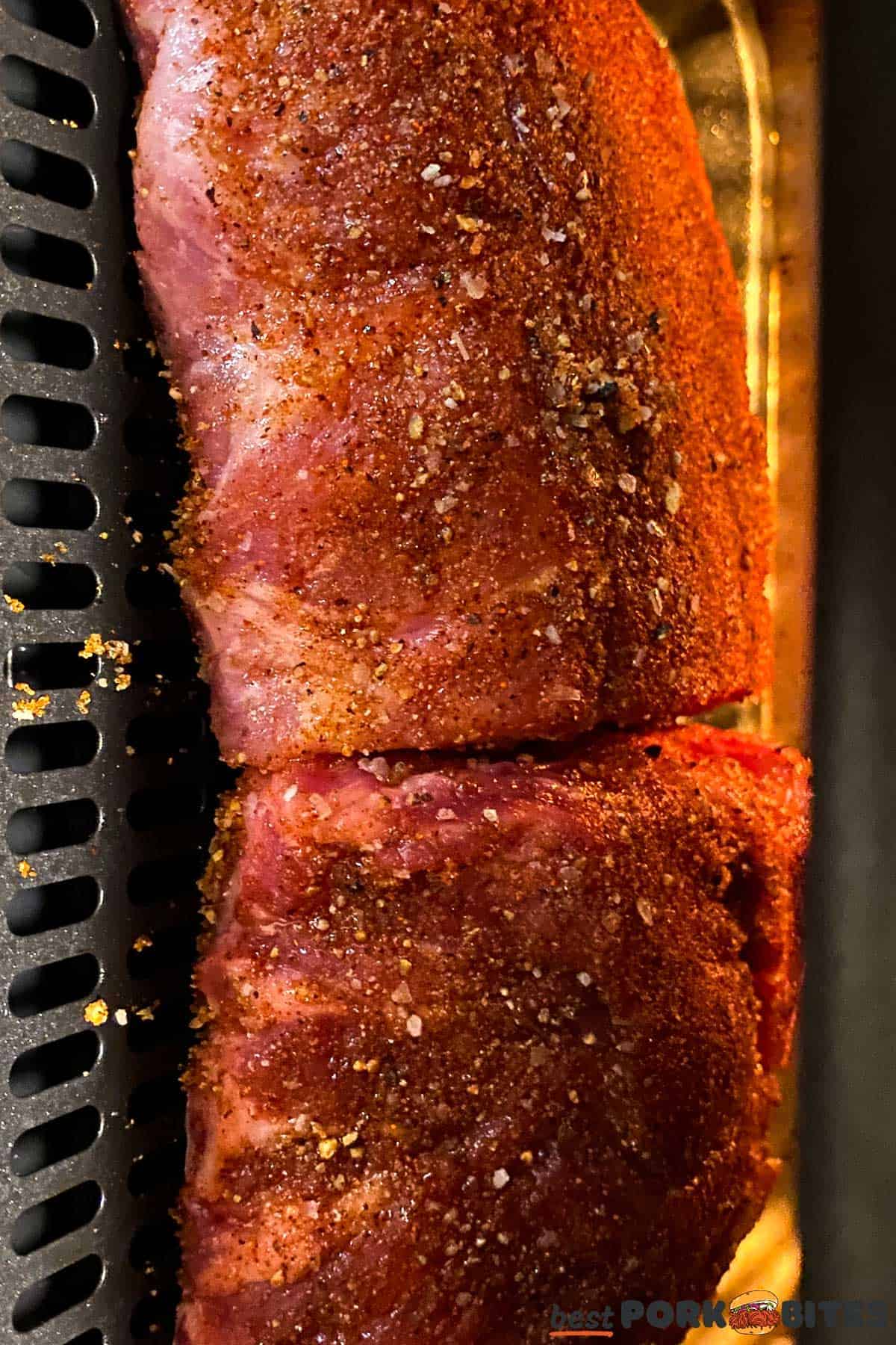 seasoned and cut raw pork ribs on an air fryer tray