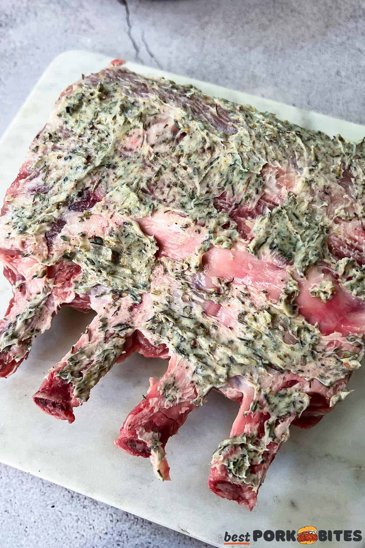 raw pork ribs coated in pork seasoning on a marble cutting board
