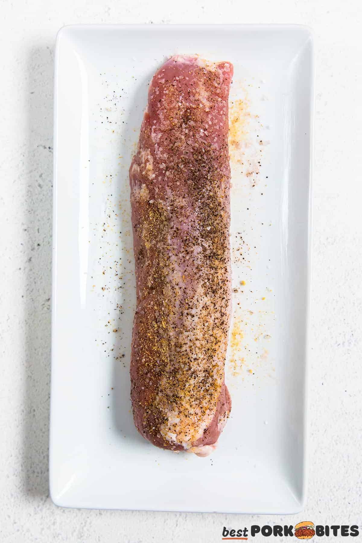 raw pork tenderloin covered in seasoning on a plate