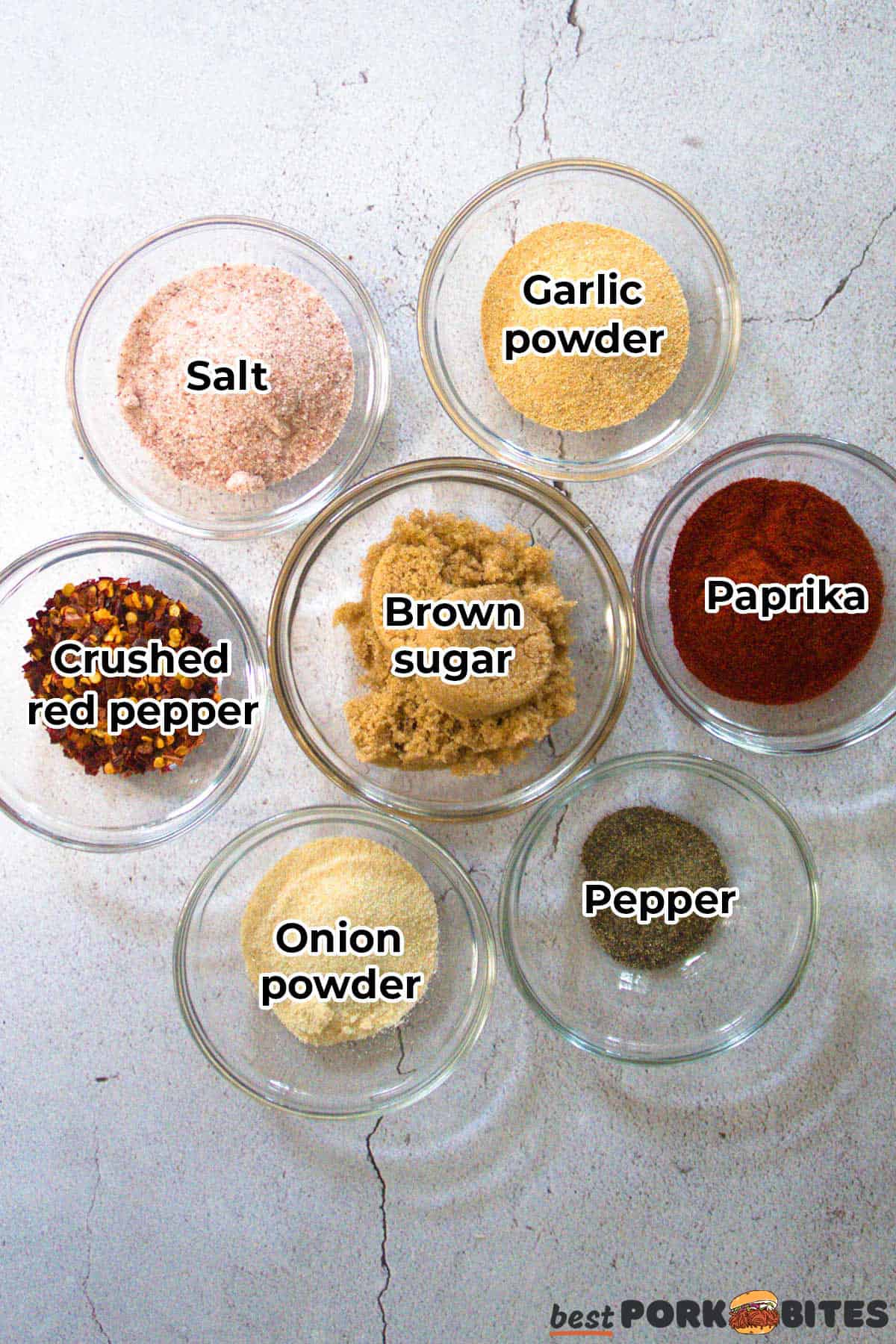 the ingredients for pork chop seasoning in separate glass dishes with labels