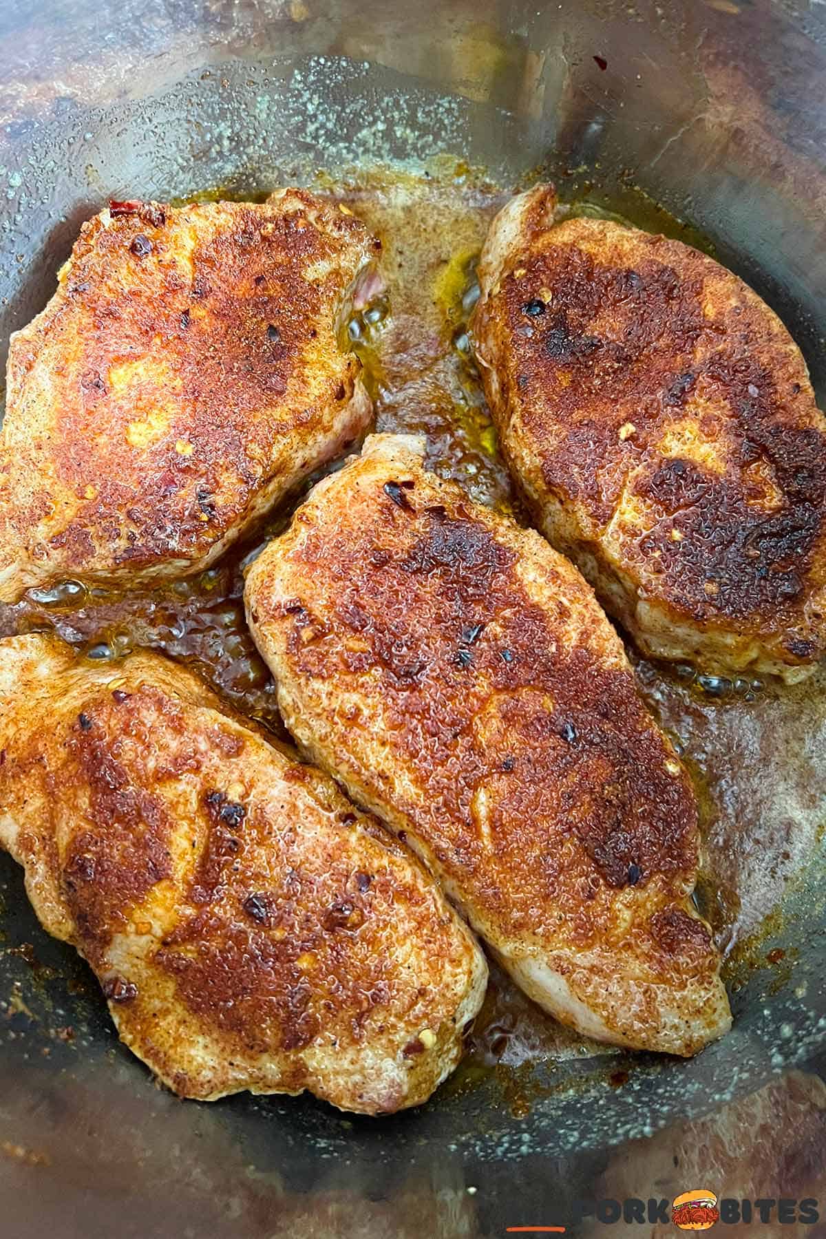 seared pork chops in a pressure cooker pot with melted butter