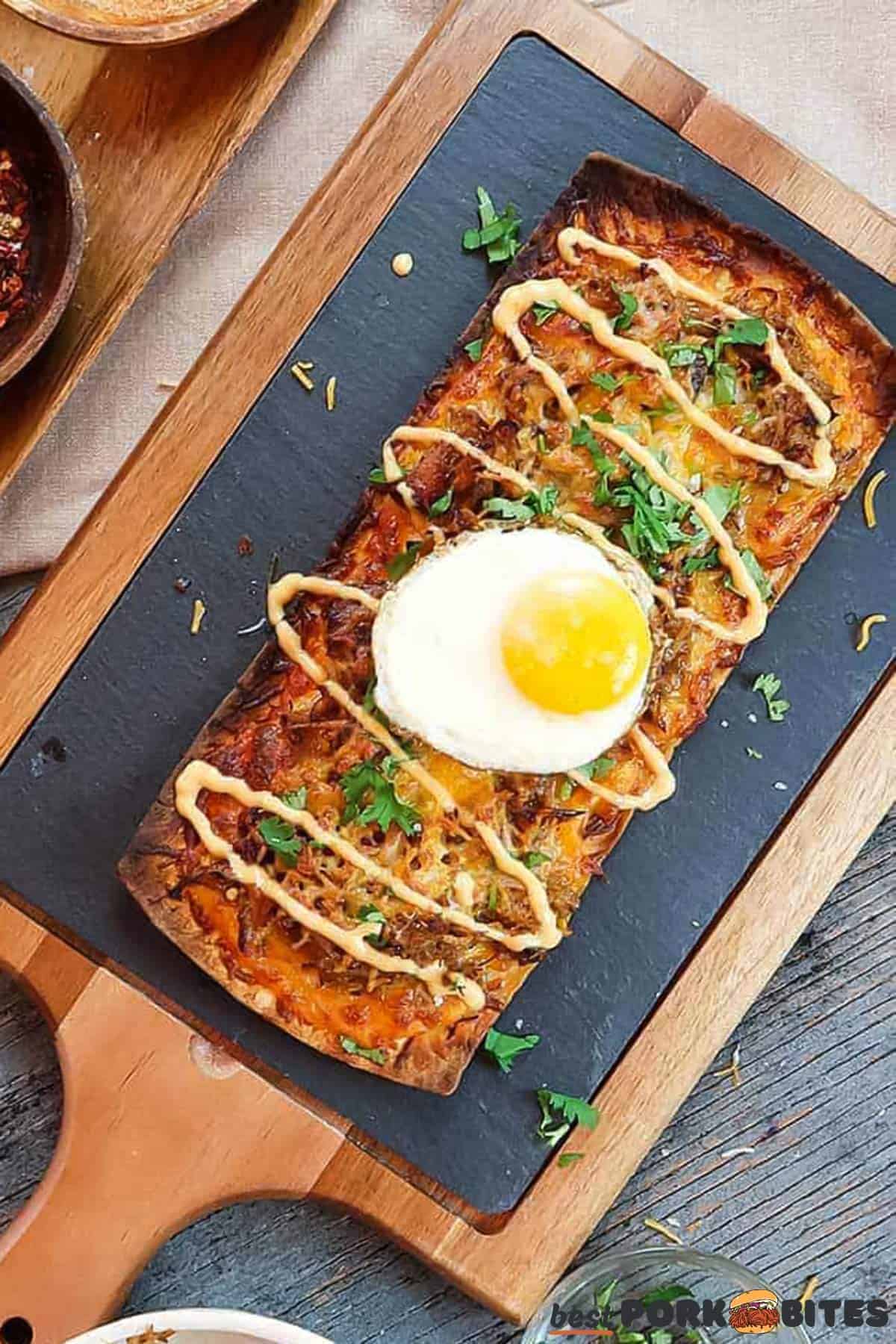 a baked pulled pork pizza on a baking sheet with garnish