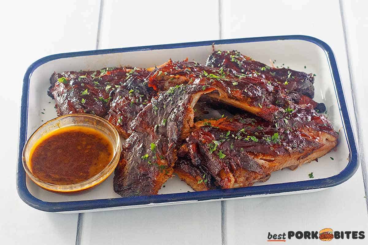 slow cooked spare ribs on a platter with sauce