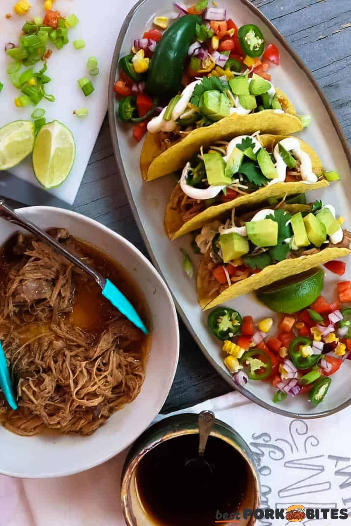 a platter of slow cooker pork tacos next to a bowl of pulled pork, a dish of sauce and a cutting board with toppings