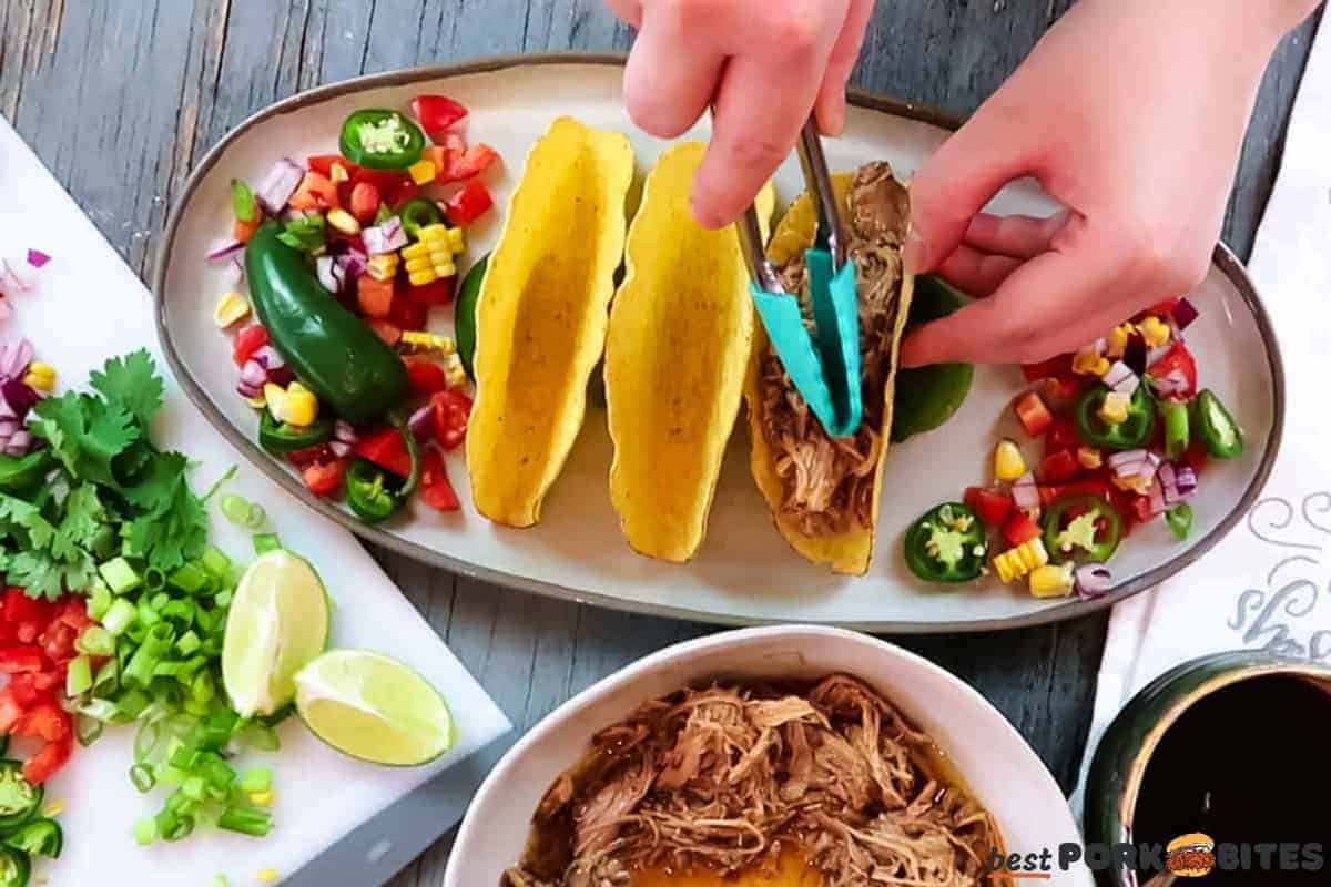pulled pork being added to hard taco shells