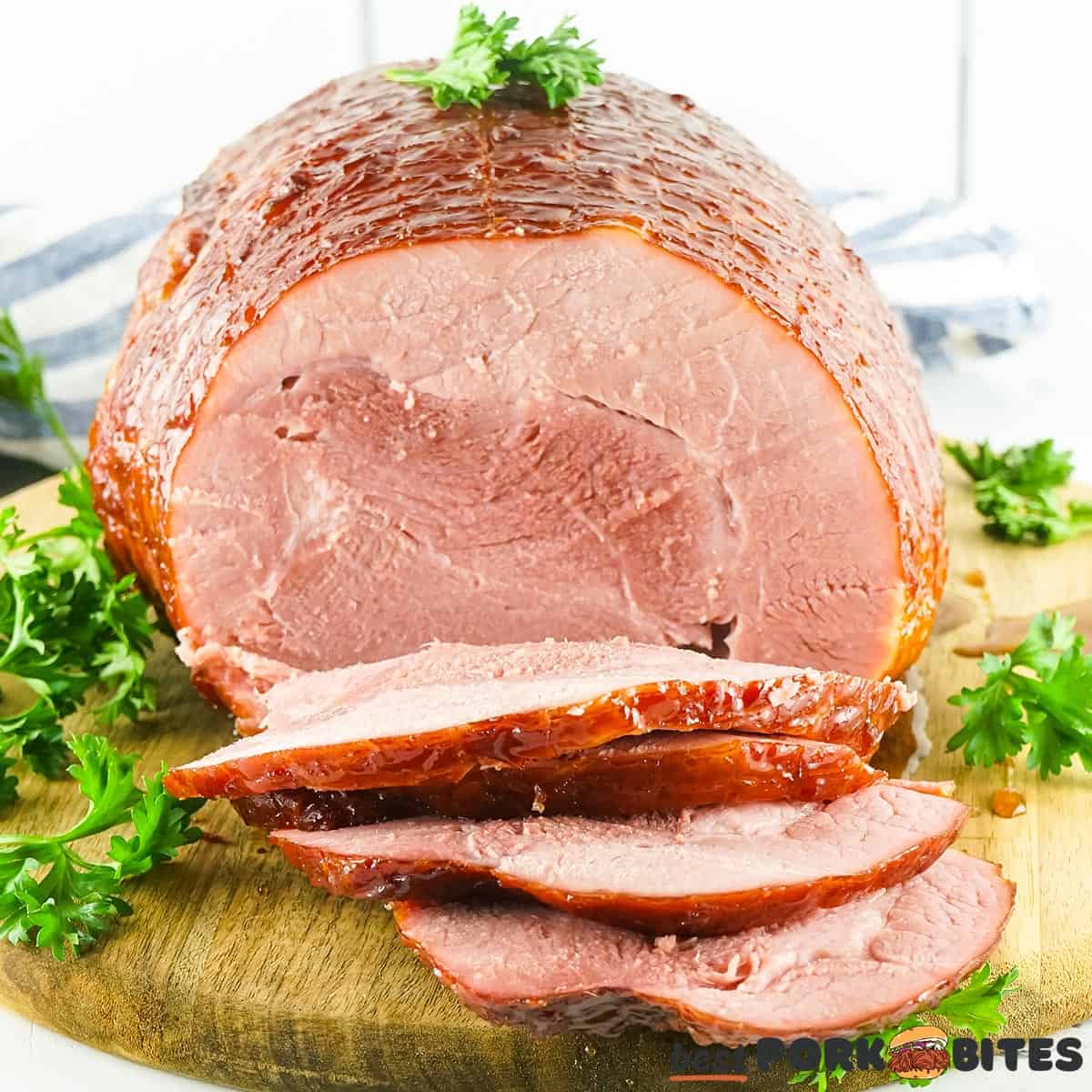 a smoked ham on a cutting board with parsley, partially sliced