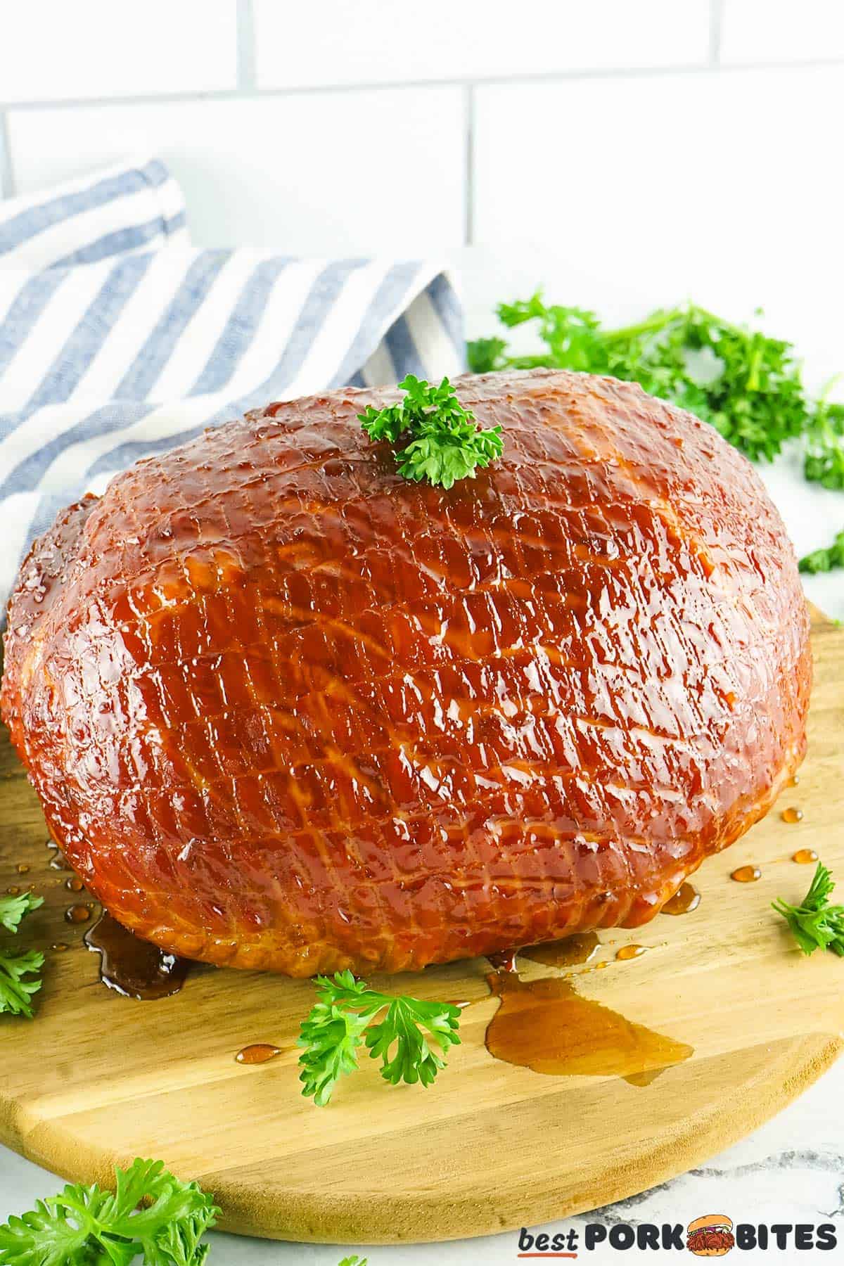 a fully glazed ham on a cutting board with parsley