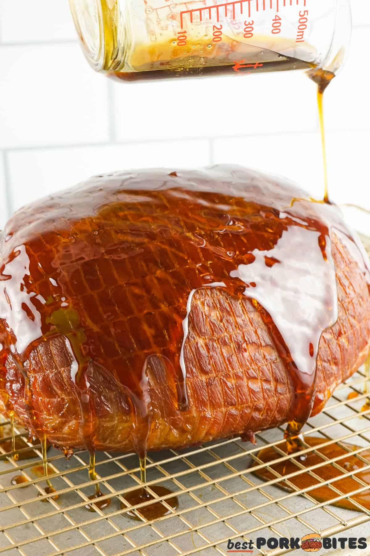 glaze being poured on a smoked ham over a wire rack