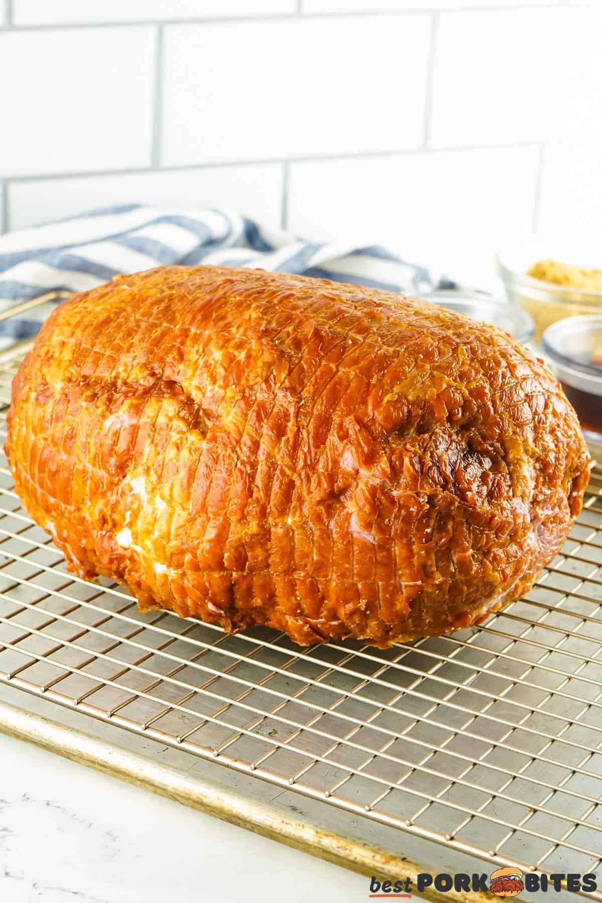 an unwrapped whole ham on a wire rack on top of a baking sheet