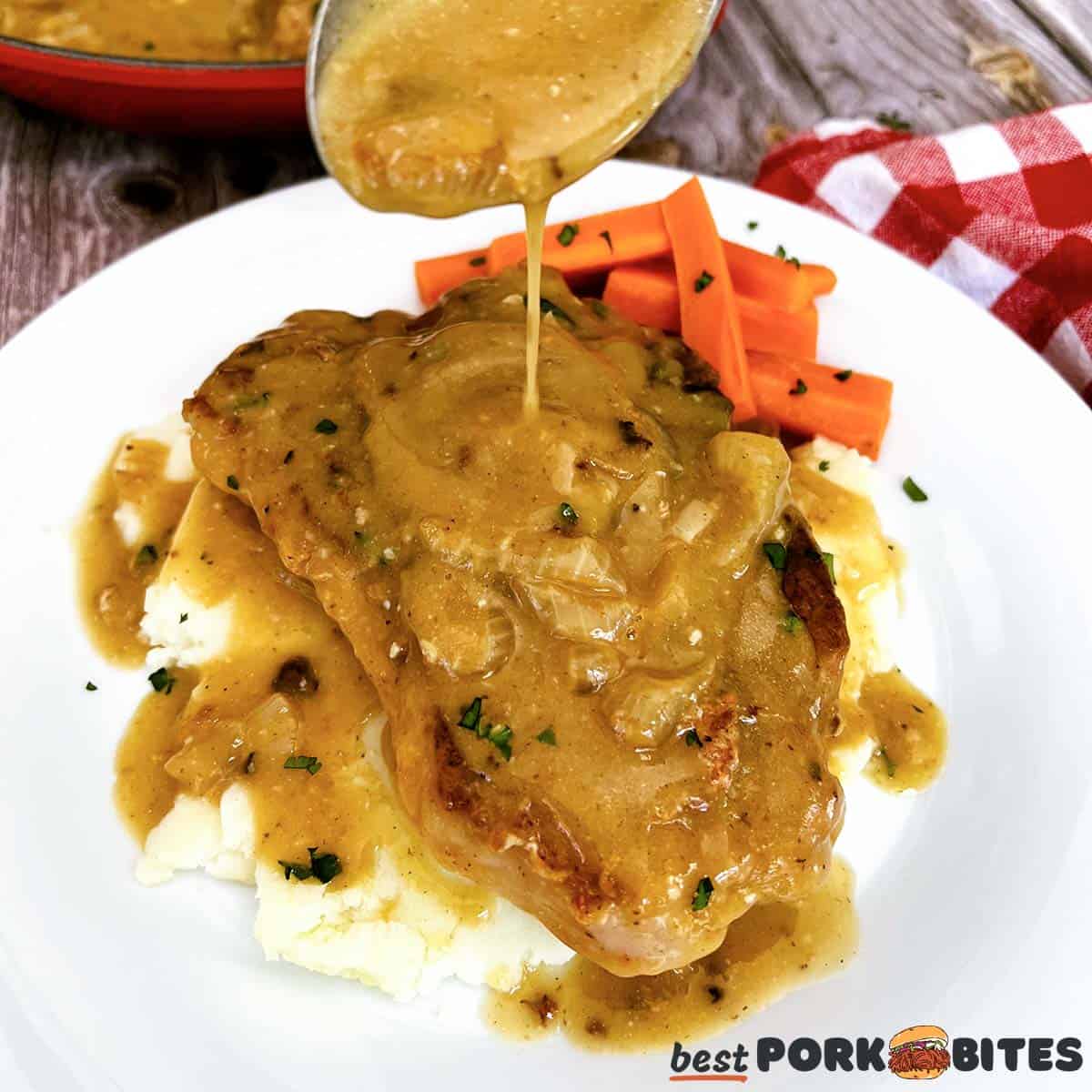 pouring gravy over smothered pork chops on a bed of mashed potatoes