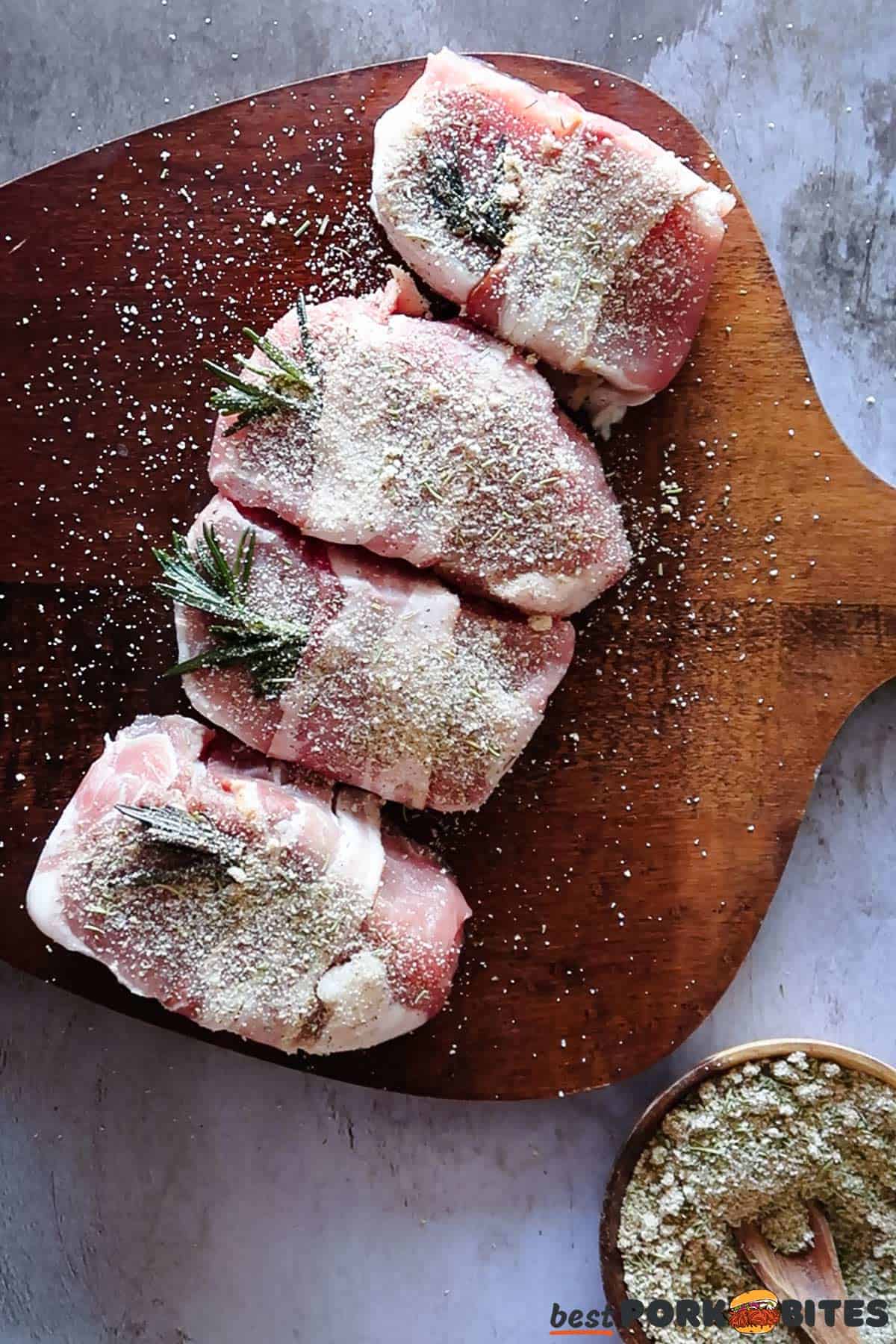 raw pork chops wrapped in bacon with rosemary and covered in rosemary seasoning