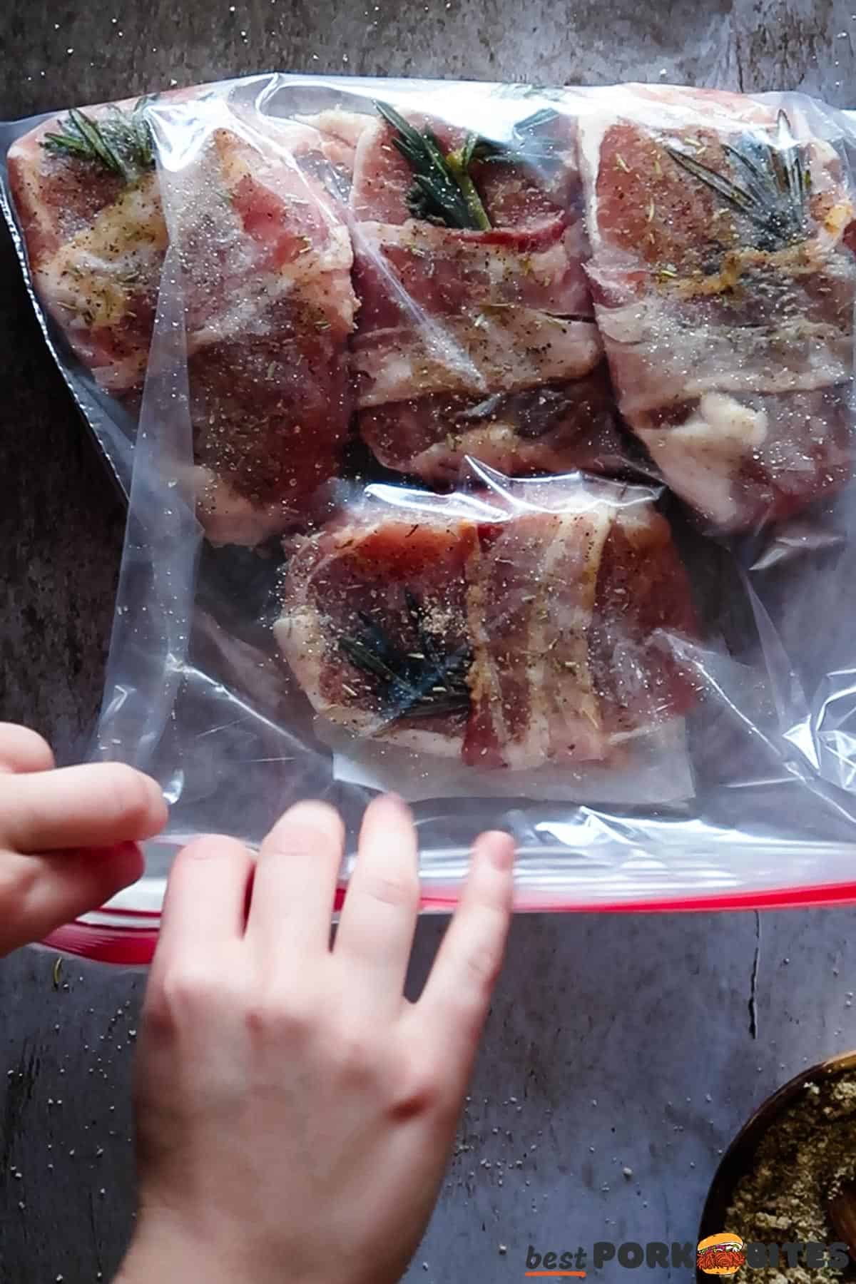 raw pork chops being sealed in a plastic bag