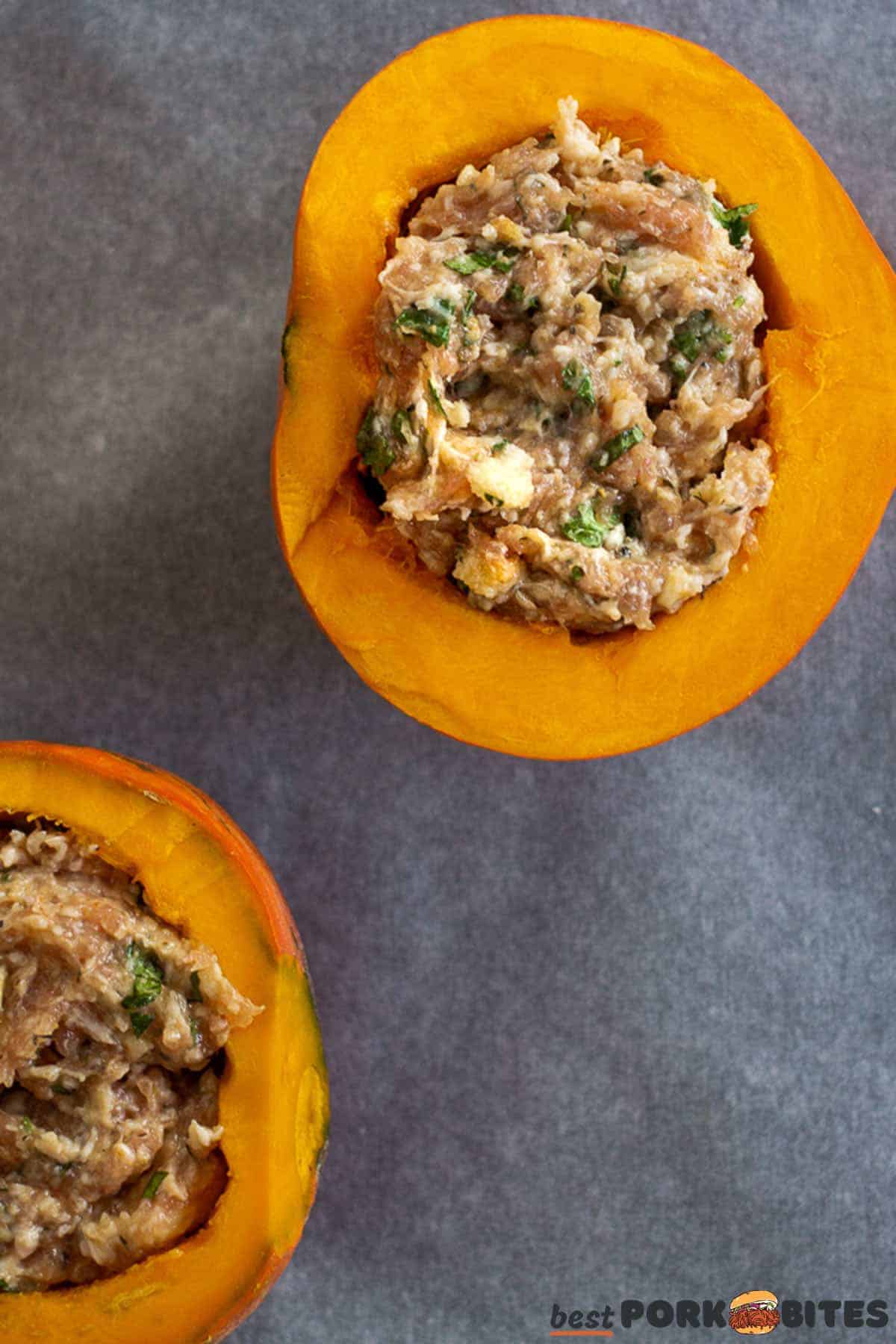 raw squash halves on a baking sheet with uncooked pork sausage stuffing